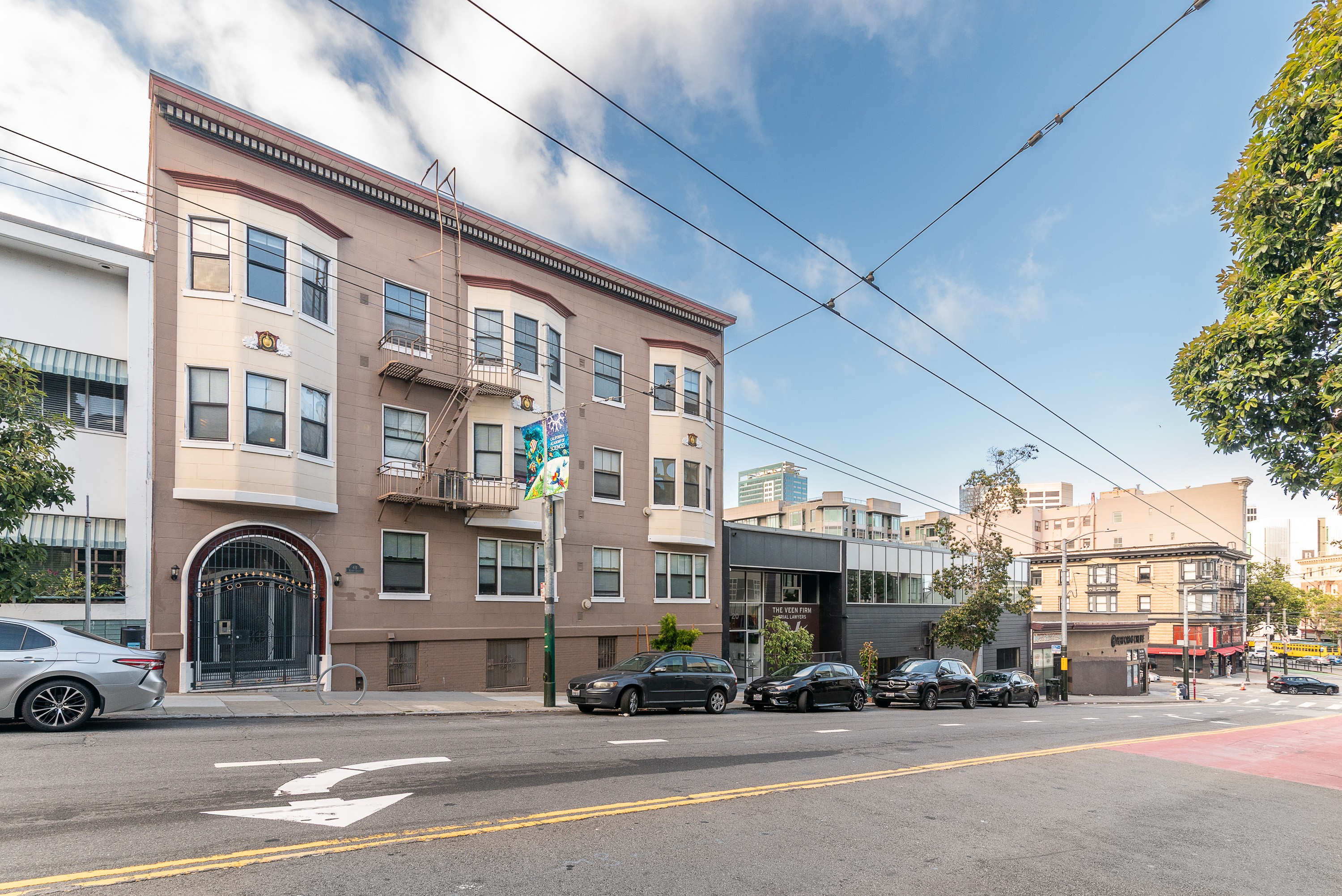A street view of a building with cars parked in front.